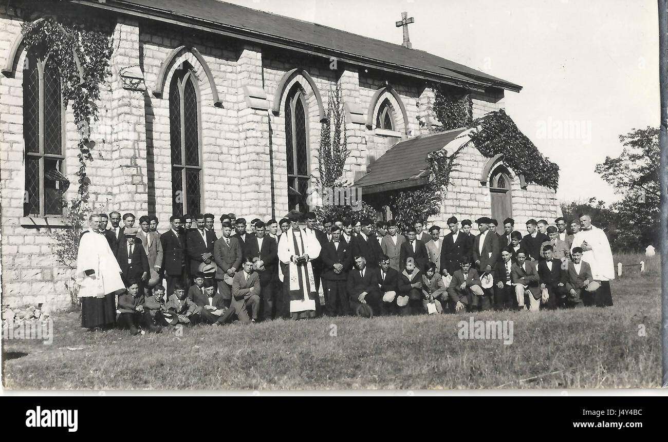 Fotografia di un gruppo di uomini e ragazzi, tre in vesti clericali, nella parte anteriore della parete sud della Chiesa di Cristo, Tyendinaga Mohawk Territory, Ontario. Foto Stock