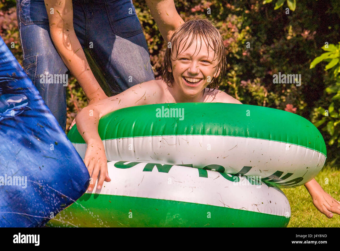 Ragazzo sorridente riproduce in ciambelle di gomma in estate sun. Foto Stock