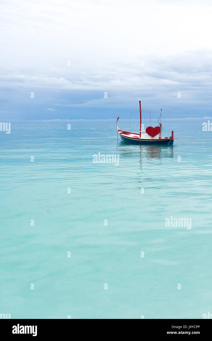 Barca con cuore rosso nell'oceano Foto Stock