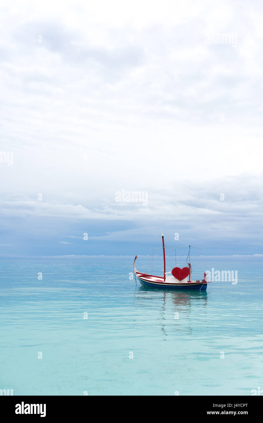 Barca con cuore rosso nell'oceano Foto Stock