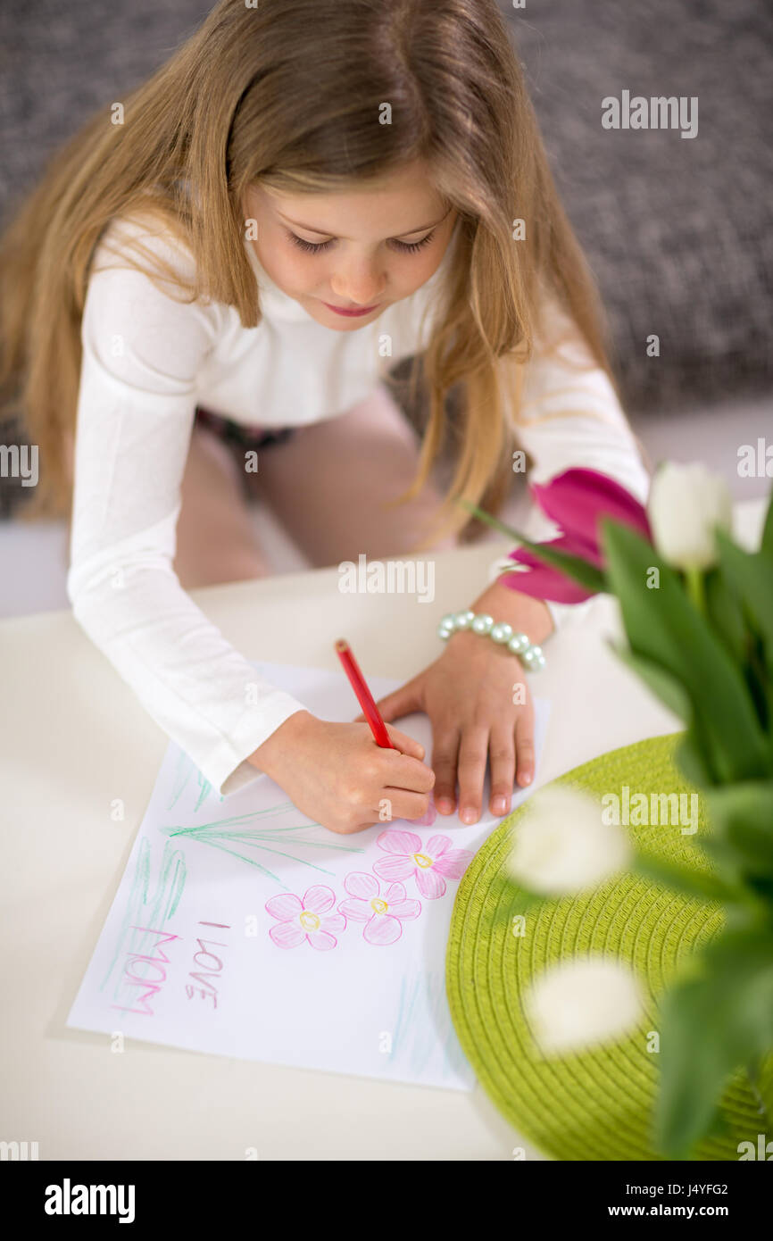 Bambina la realizzazione di una scheda per la sua mamma, festa della mamma Foto Stock