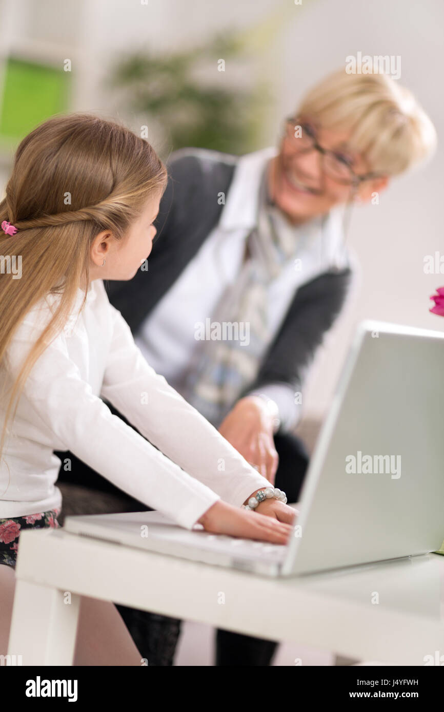 Bambina utilizzando laptop con la nonna a casa Foto Stock