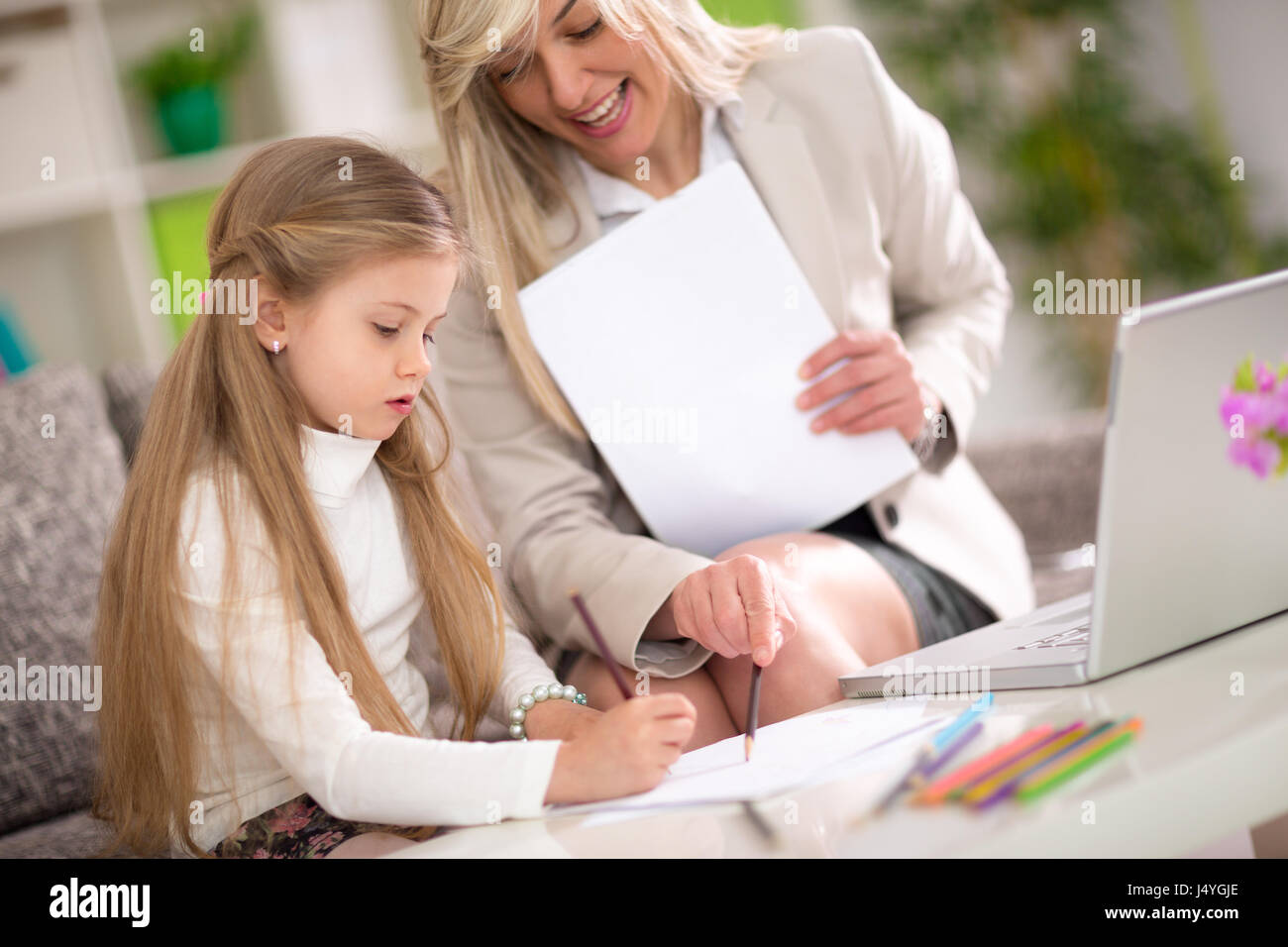 Ragazza carina imparare a casa sua madre aiutare Foto Stock