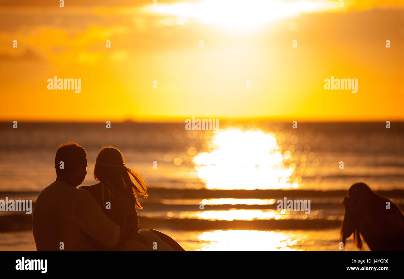 Gli sposi con un fotografo sulla spiaggia, prendendo immagini romantiche per ricordare Foto Stock