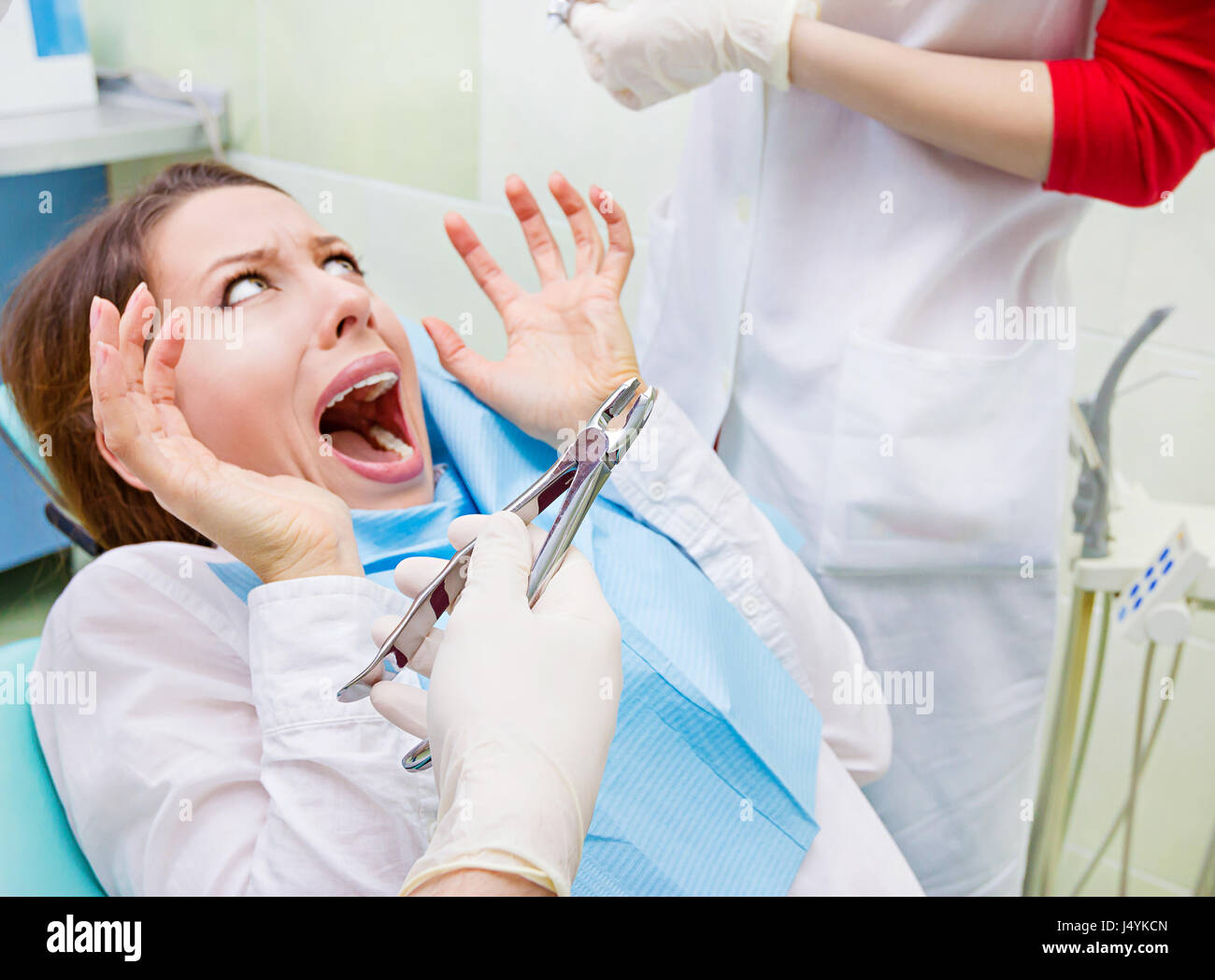 Closeup ritratto giovane ragazzina terrorizzata donna spaventata a visita dal dentista, ubicazione in cattedra, urlando, aperto bocca, non desidera procedura dentale la perforazione Foto Stock