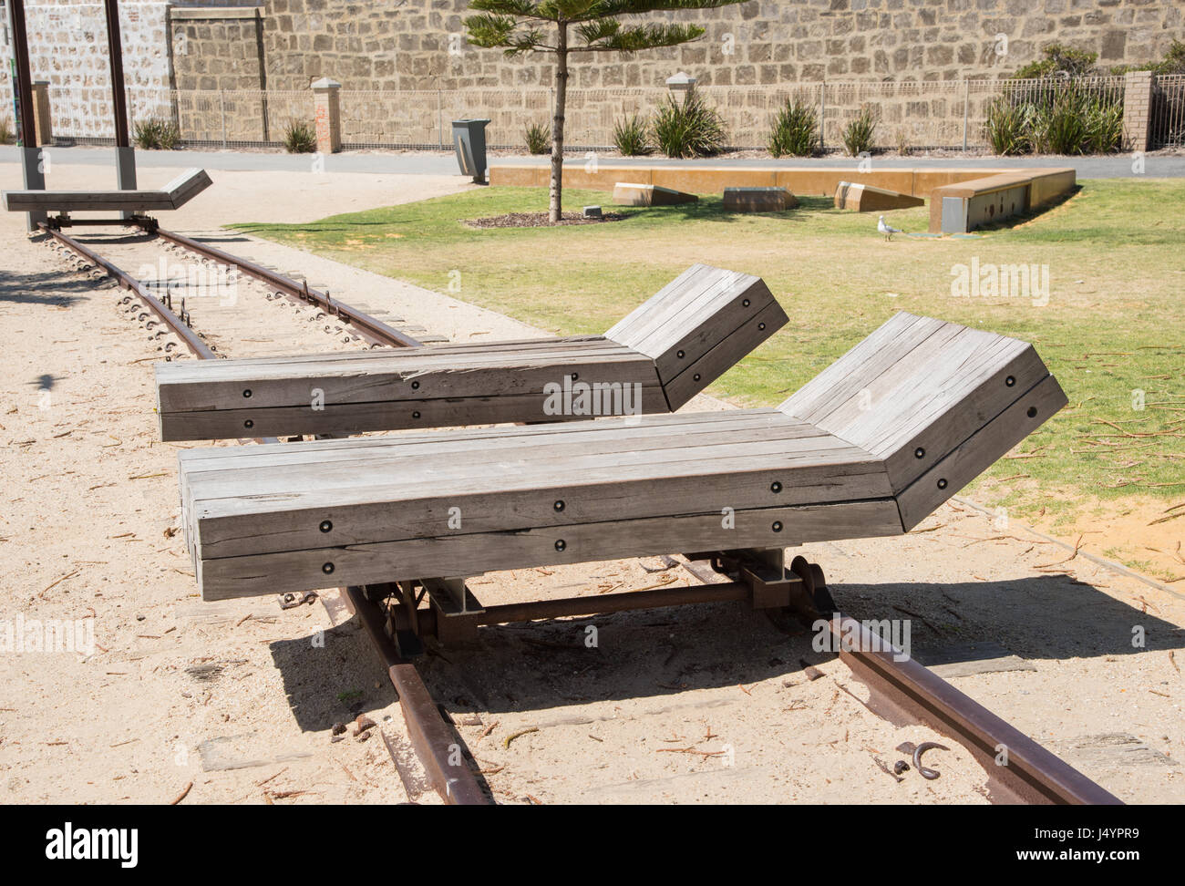 Legno di due sedie a sdraio su binari ferroviari su sabbia in outdoor impostazione costiere a Fremantle, Western Australia. Foto Stock