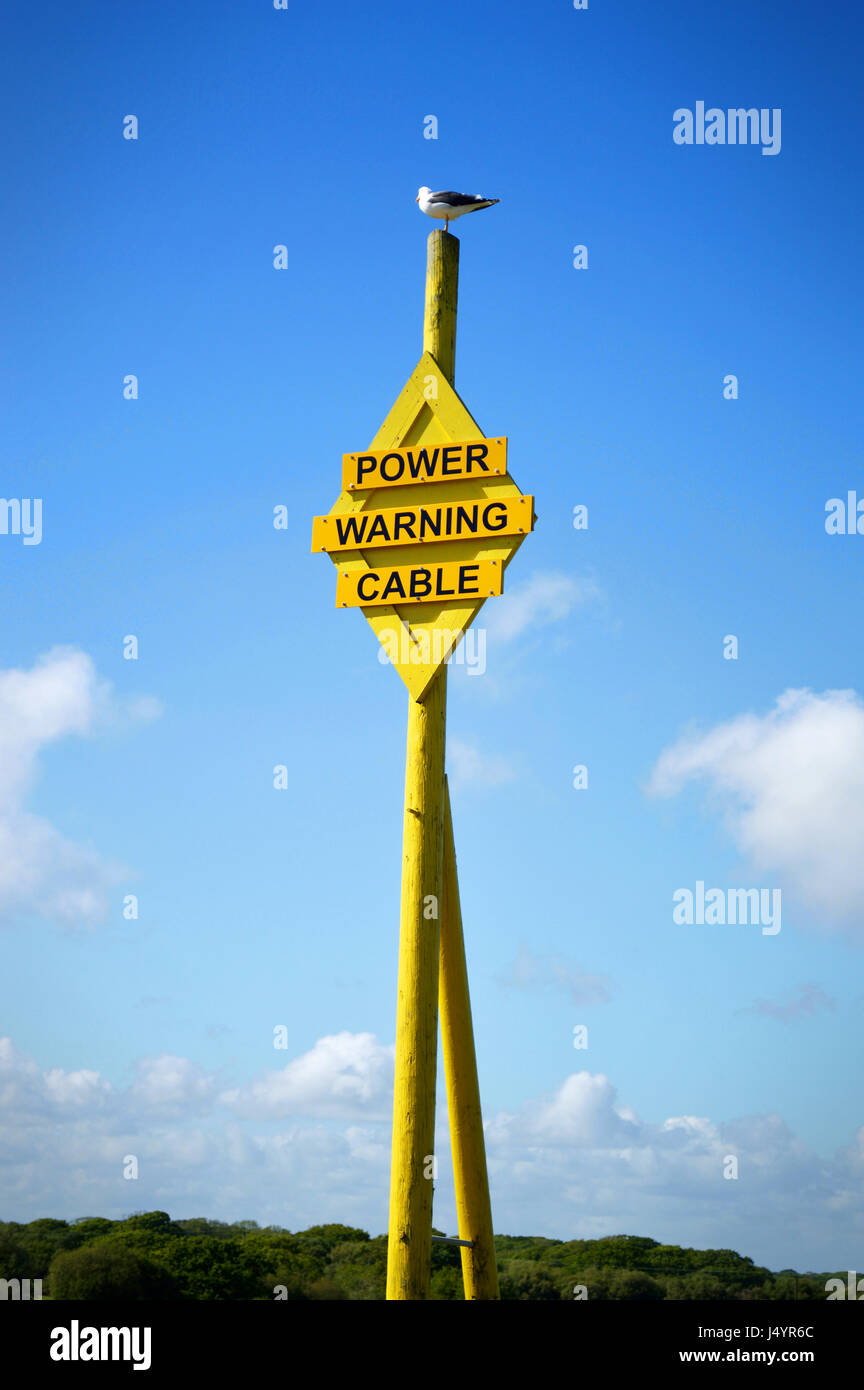 Un simbolo giallo di avvertimento di subacquei cavi di potenza a Lepe beach in Hampshire, Regno Unito Foto Stock