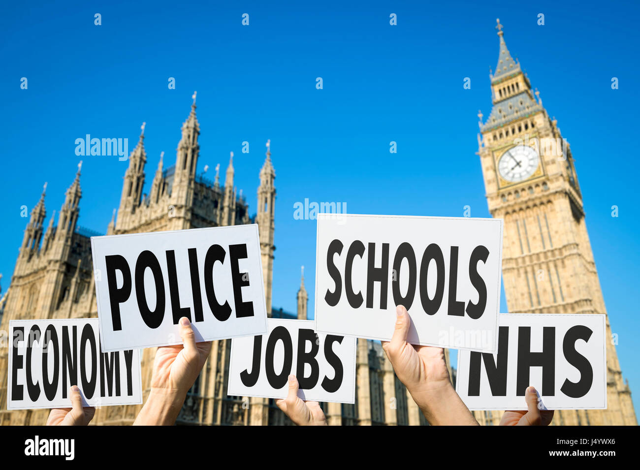 Mani con segni elezione questioni come l'economia, la polizia, i lavori, le scuole e il NHS fuori casa del Parlamento presso il Palazzo di Westminster, Londra Foto Stock