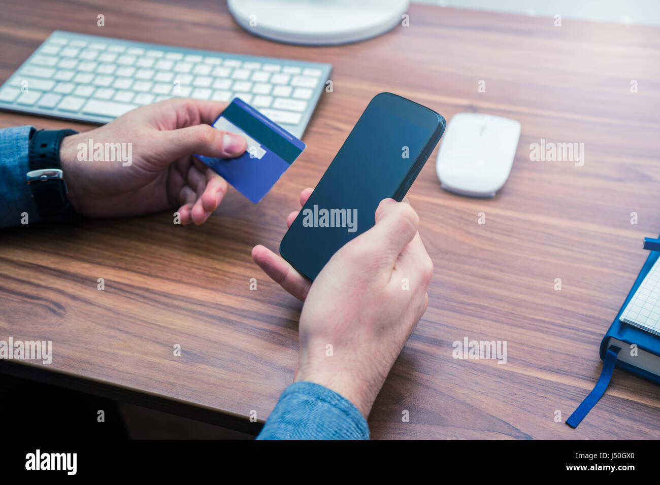 Mani tenendo la carta di credito e una digitazione sul telefono cellulare acquisto online Foto Stock
