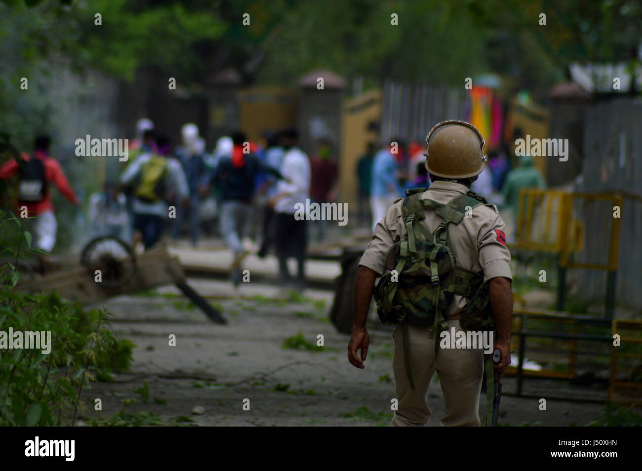 Srinagar Kashmir. 15 Maggio, 2017. Gli studenti del Kashmir scagliare pietre su poliziotti indiani come uno strappo con un guscio di fumo esplode vicino a loro durante uno scontro a Srinagar, Indiano Kashmir controllata, lunedì 15 maggio, 2017. Gli studenti sono stati si scontrano sempre più con le forze di governo attraverso indiano-tenutasi il Kashmir dopo le truppe hanno perquisito un collegio nella città meridionale di Pulwama il mese scorso. Credito: PACIFIC PRESS/Alamy Live News Foto Stock