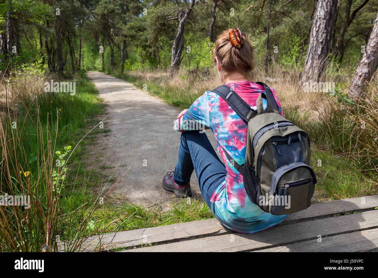 Donna olandese con zaino seduta sul sentiero forestale Foto Stock