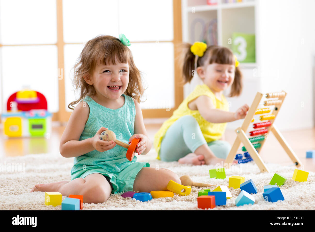 Ci sono bambini che giocano con abacus e costruttore di giocattoli sul pavimento a scuola o a casa. Apprendimento precoce concetti. Foto Stock