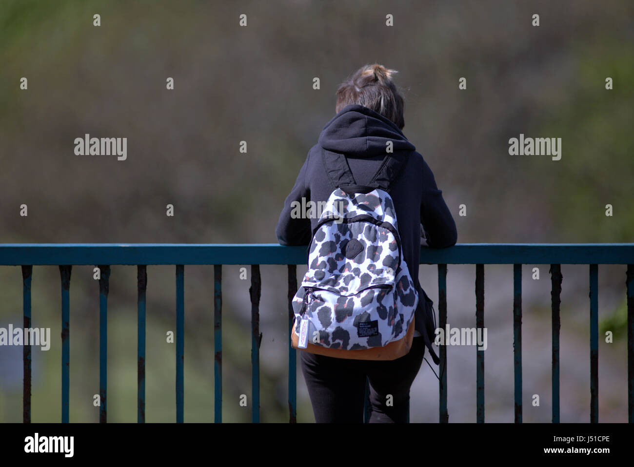 Adolescente adolescente da solo contemplando fissando la distanza a fianco di ringhiere in ferro Foto Stock