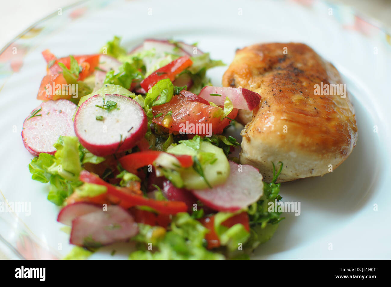 Cotta di petto di pollo con insalata di verdure su una piastra bianca vicino. Messa a fuoco selettiva. Foto Stock