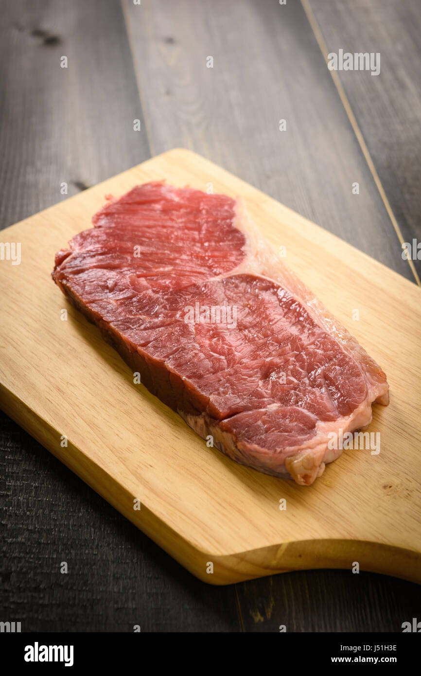 Materie di manzo bistecca di controfiletto su tagliere in legno, Foto Stock