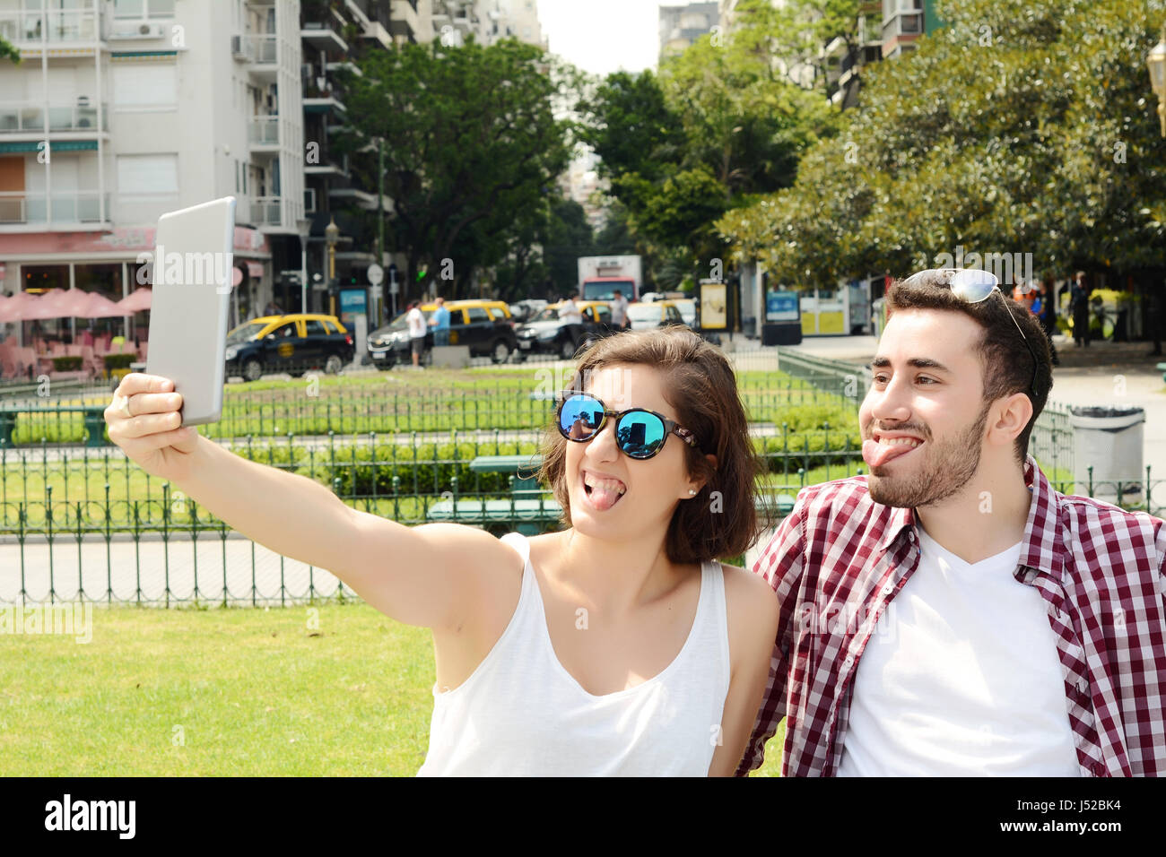 Ritratto di una giovane bella giovane tenendo selfie con tavoletta digitale. All'esterno. Foto Stock