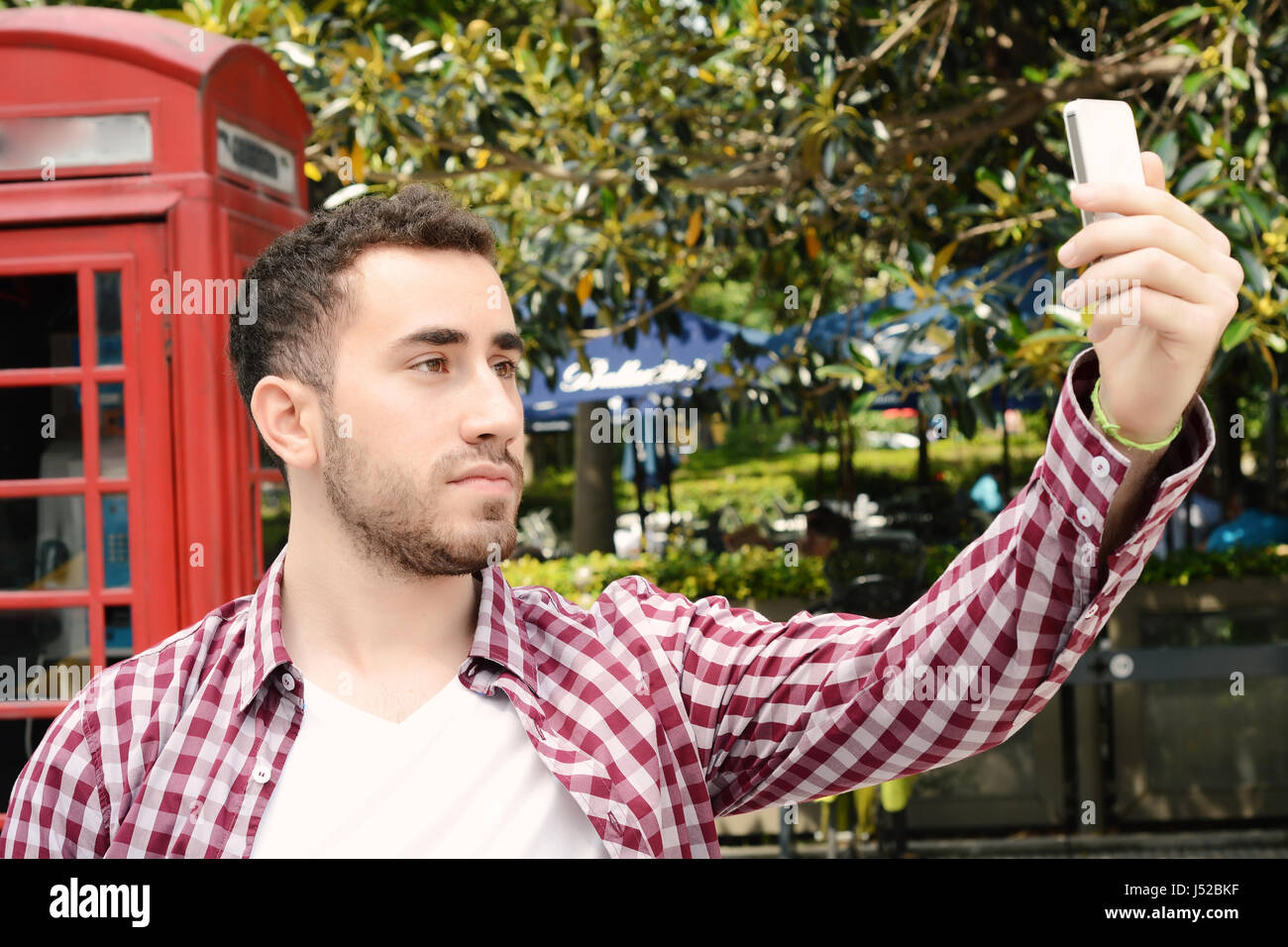 Ritratto di un giovane uomo latino tenendo un selfie con lo smartphone. All'esterno. Foto Stock