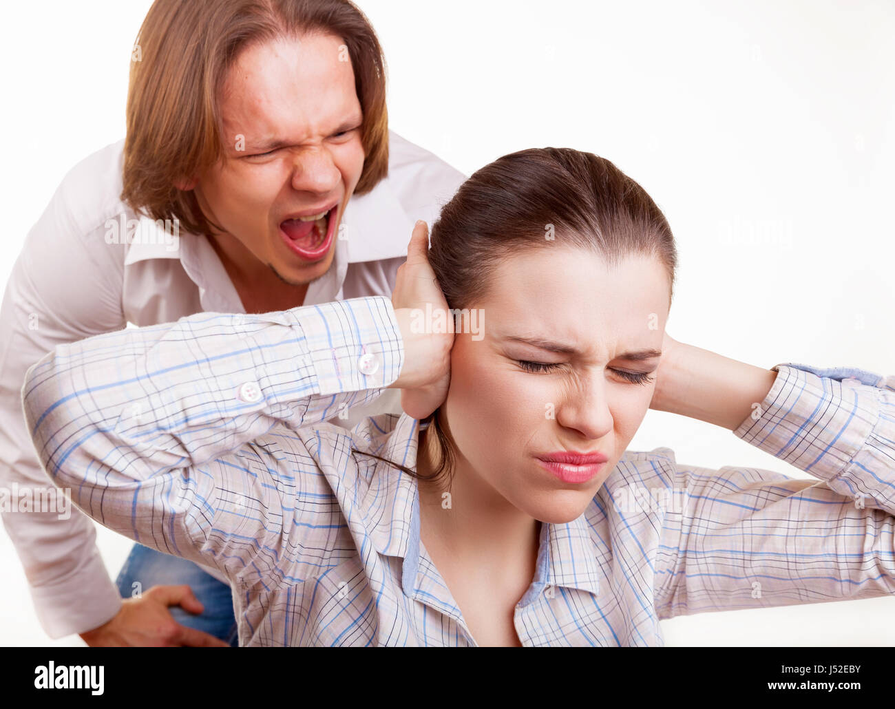 Enraged uomo grida al giovane donna. Donna che copre le sue orecchie con le mani. Isolato su sfondo bianco Foto Stock