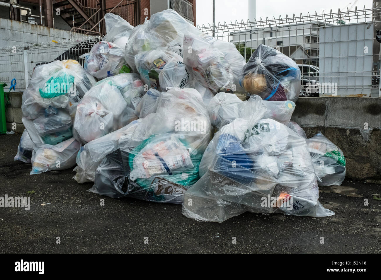 Plastica sacchi della spazzatura in un parcheggio in attesa di essere raccolti a Tokyo Foto Stock