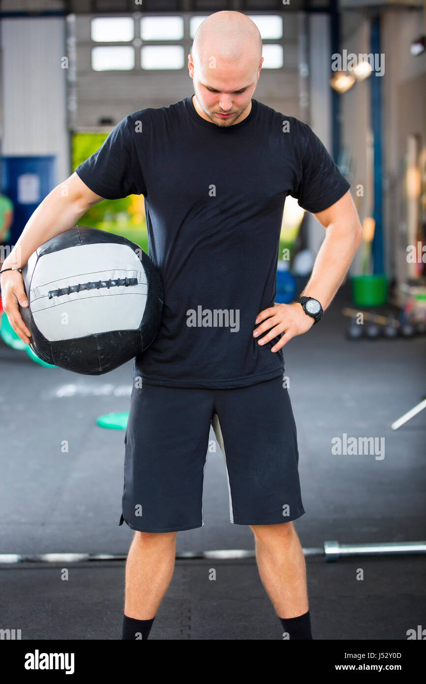Forte atleta maschio tenendo palla medica nel Club Salute Foto Stock