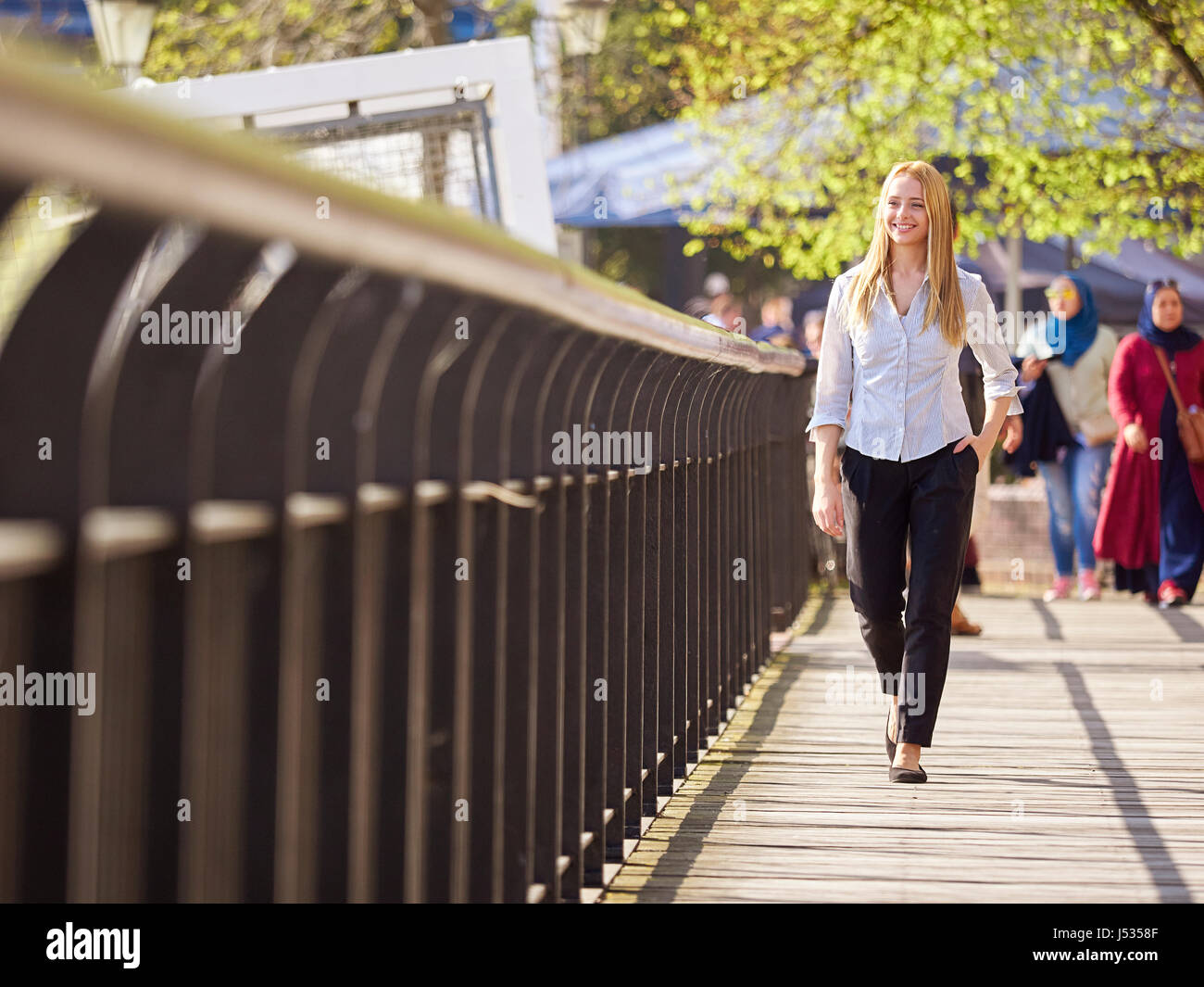 Giovane donna camminando lungo il fiume Tamigi, Londra Foto Stock