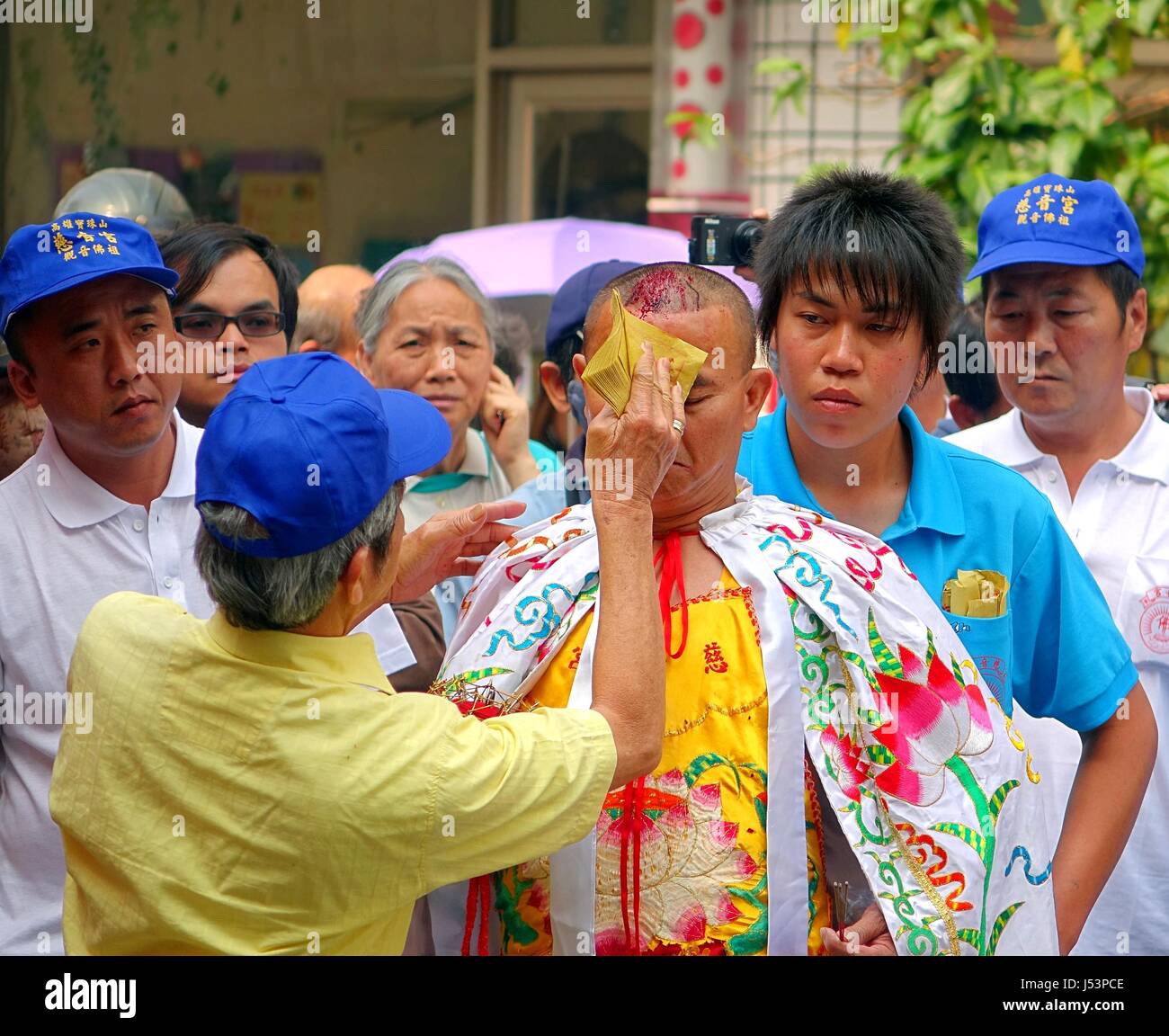 KAOHSIUNG, Taiwan -- Marzo 16, 2014: ad una cerimonia religiosa di un uomo non identificato utilizza ghost soldi per ripulire il sangue da un auto-inflitte avvolto sul Foto Stock