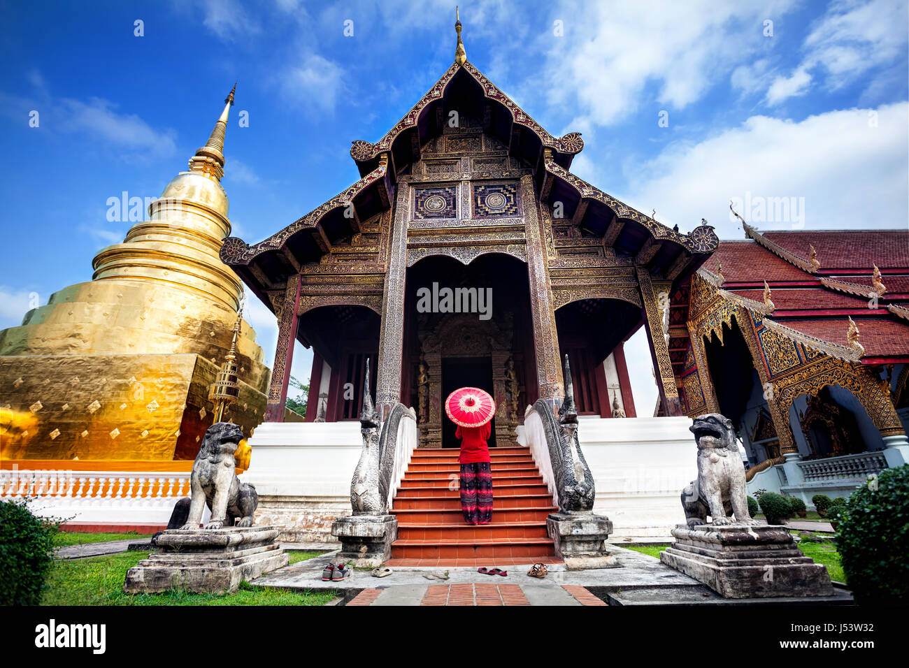 Donna con turistico rosso tailandese tradizionale ombrellone vicino a Golden tempio Wat Phra Singh in Chiang Mai Thailandia Foto Stock