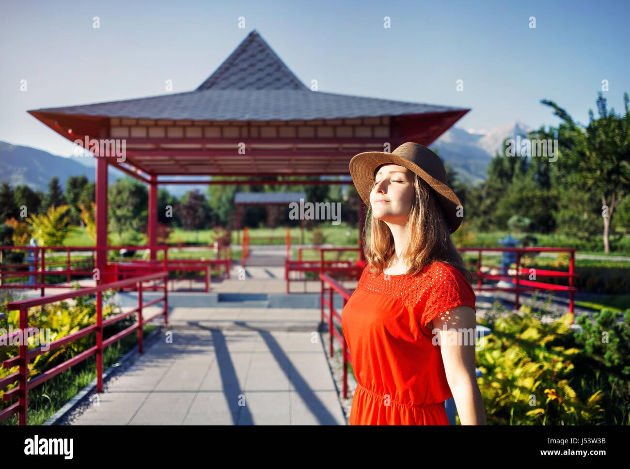 Ritratto di donna bella in abito arancione e hat vicino la pagoda nel giardino giapponese Foto Stock