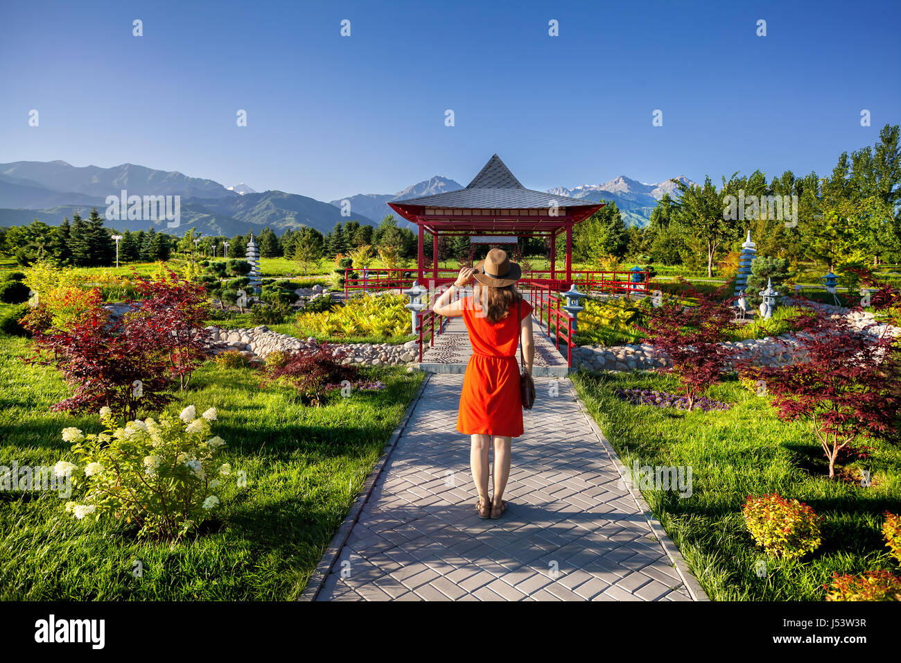 Donna in abito arancione con hat guardando la Pagoda giapponese giardino Foto Stock