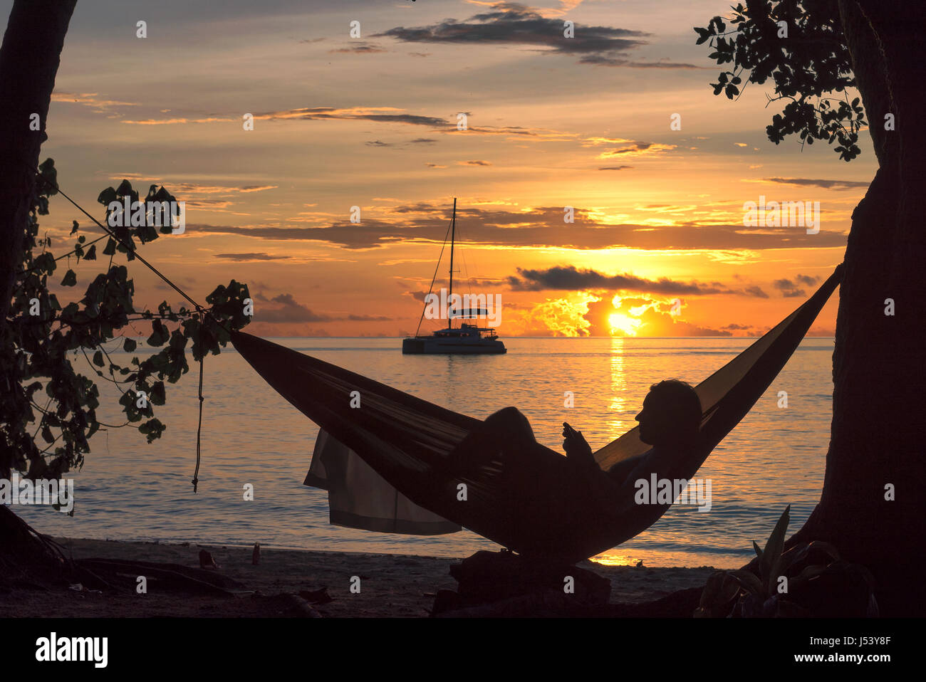 Le vacanze in spiaggia, silhouette di donna lettura in amaca al tramonto sull isola tropicale. Foto Stock