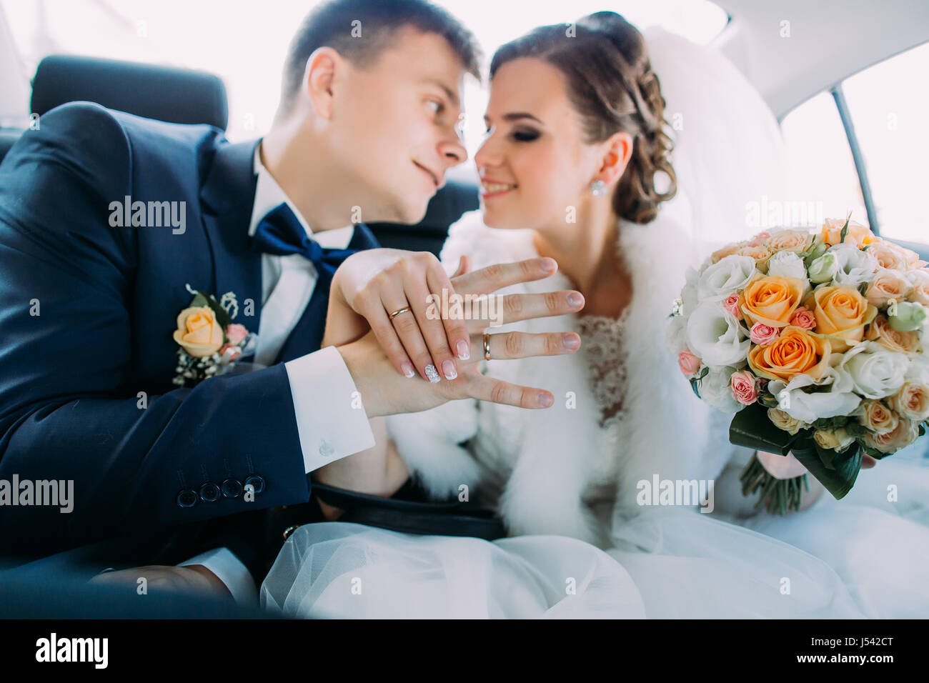 Il bel ritratto di felice sposi mostrando le mani con le fedi mentre è seduto in macchina. Foto Stock