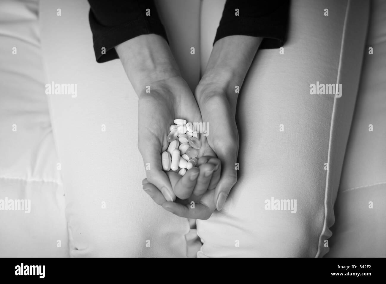 Giovane donna premuto il tentativo di commettere suicidio, lei sta tenendo in mano un grappolo di pillole nelle sue mani Foto Stock