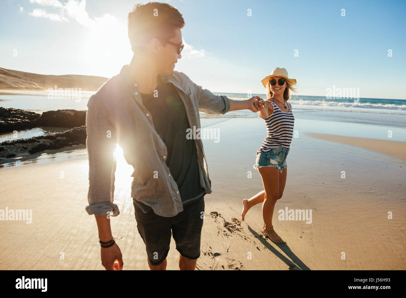 Colpo di amorevole coppia giovane tenendo le mani e camminando sulla riva del mare. Giovane uomo e donna camminando sulla spiaggia un giorno d'estate. Foto Stock