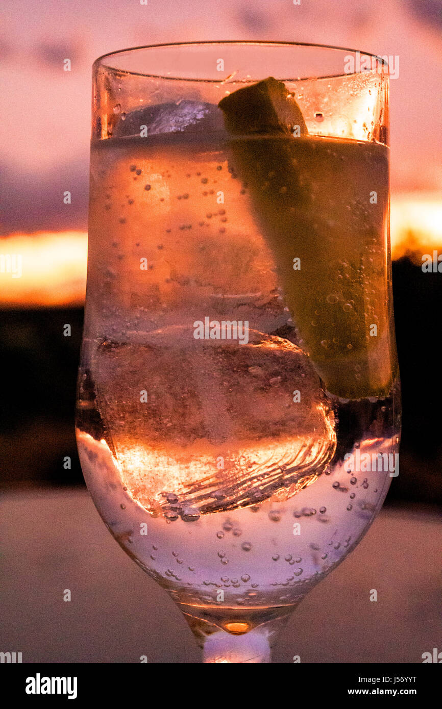 Bicchiere di bevande con ghiaccio e limone al tramonto Foto Stock