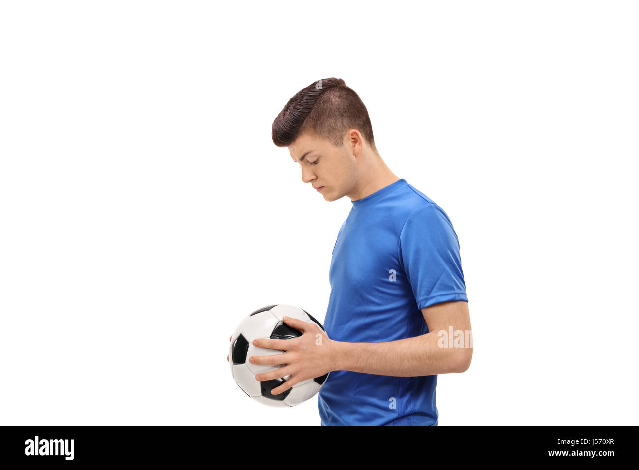 Profilo di colpo un triste teenage giocatore di calcio tenendo un calcio isolati su sfondo bianco Foto Stock