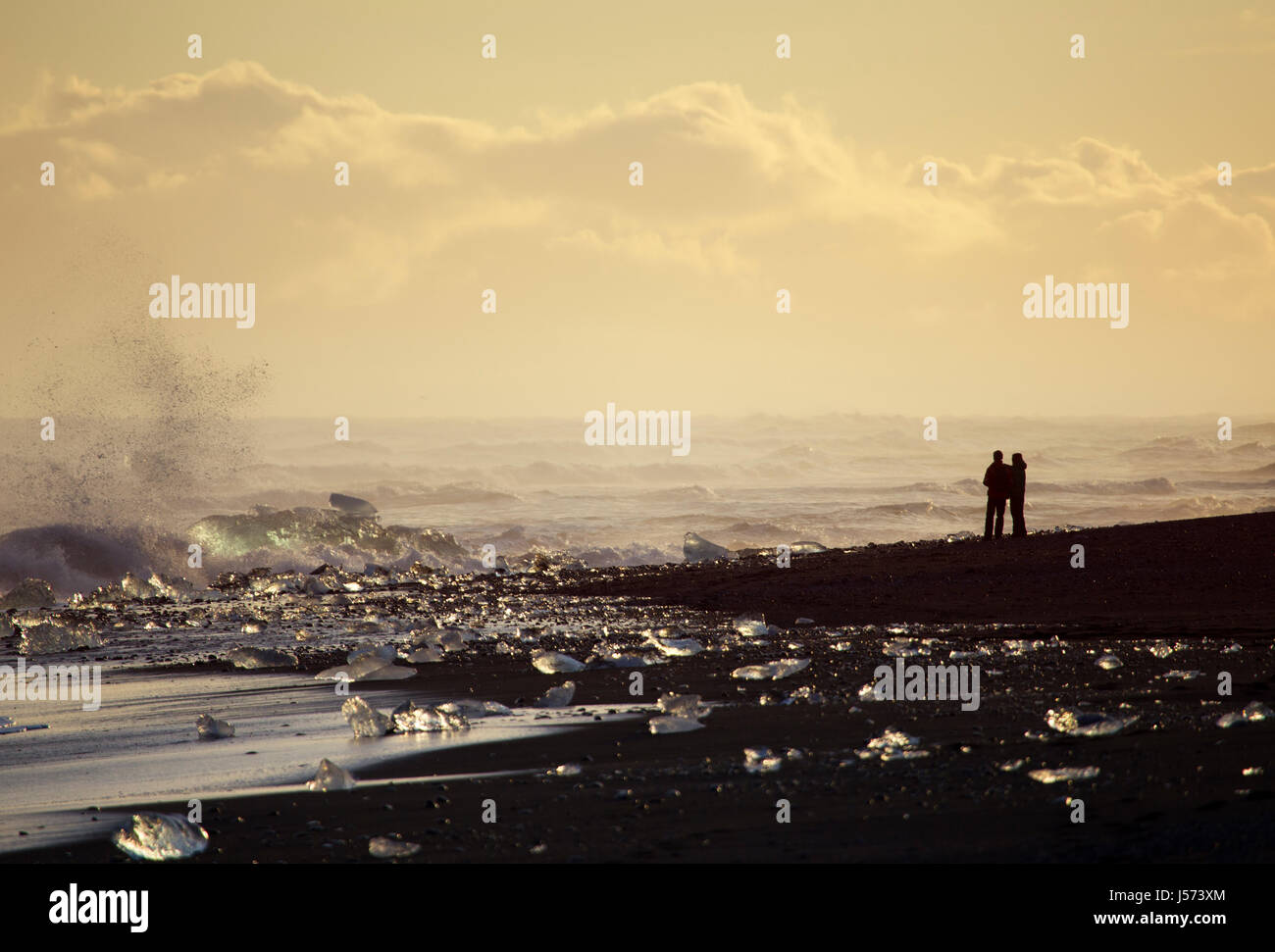 Due persone godendo del tramonto al diamante spiaggia vicino alla laguna glaciale nel sud est dell'Islanda Foto Stock
