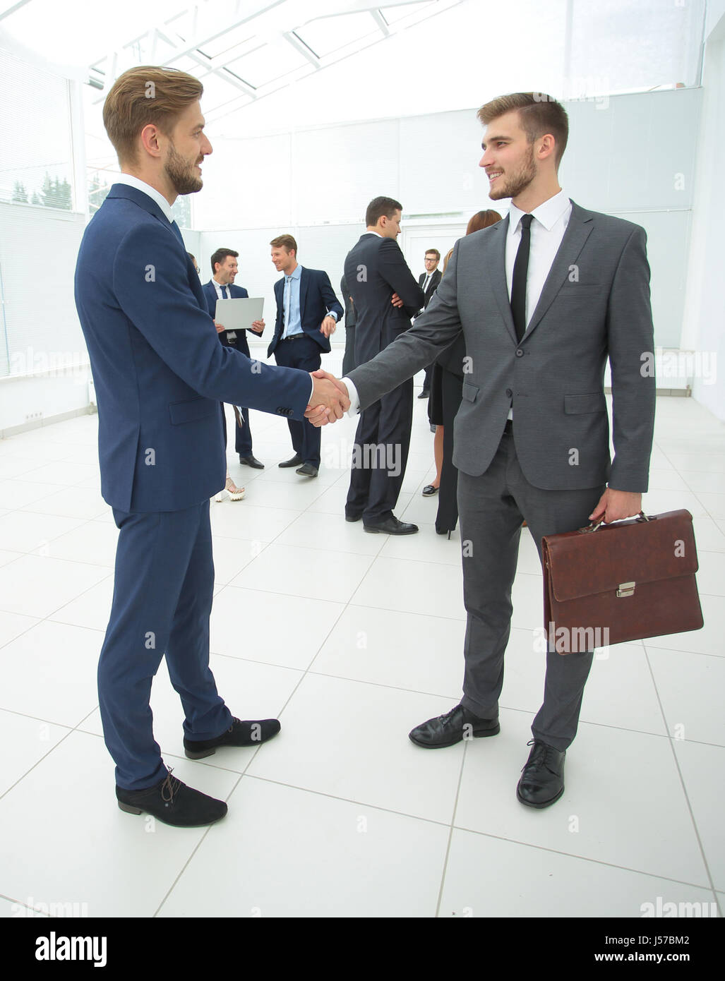 Due bello uomini d' affari rendendo stretta di mano in un ufficio Foto Stock