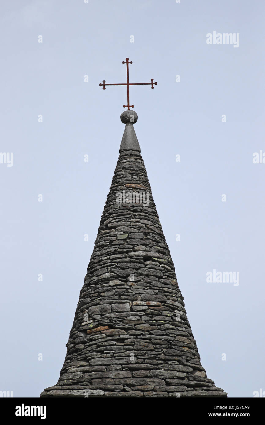 Croce di ferro sulla sommità della antica chiesa e il campanile costruito con blocchi di granito contro il cielo blu Foto Stock