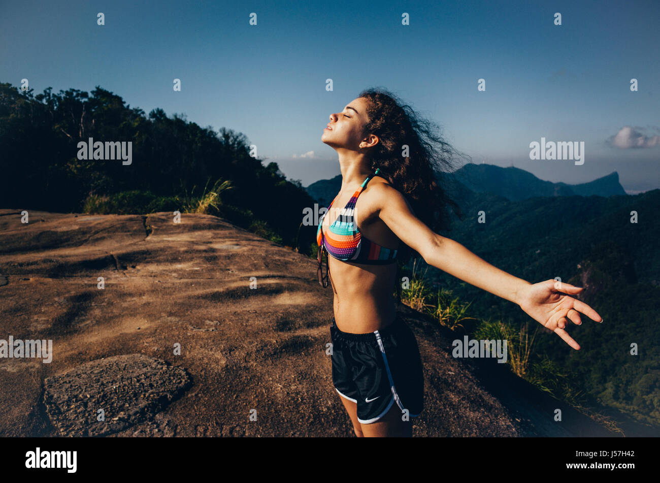 Giovani liberi spiriti donna gode del vento a Pedra Bonita montagna in Rio de Janeiro, Brasile Foto Stock