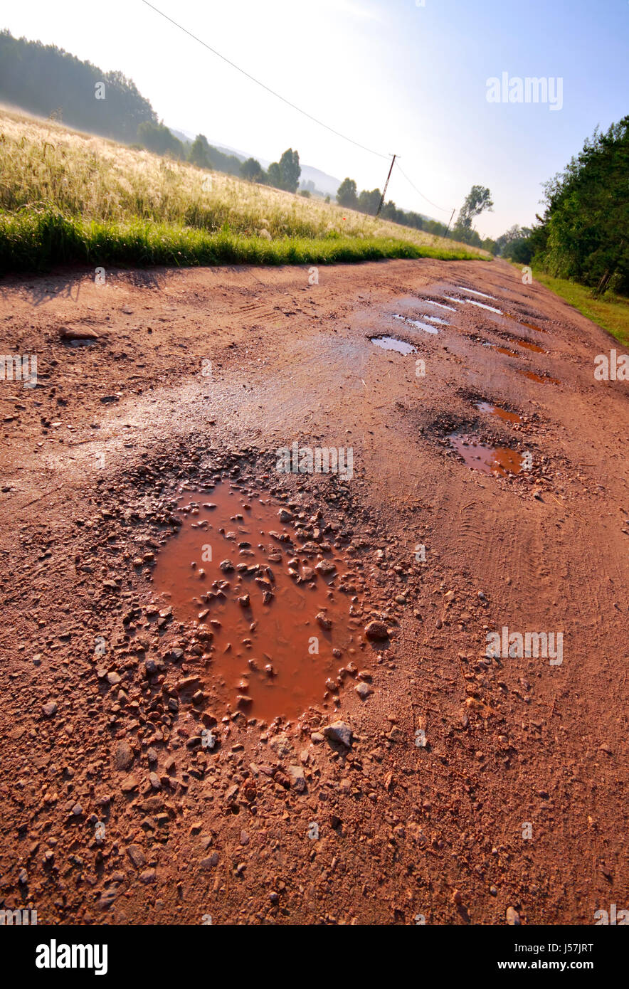 Locali di argilla rossa su strada bagnata con fori circondato da campi e foreste. Riprese oblique. Polonia, Swietokrzyskie. Foto Stock