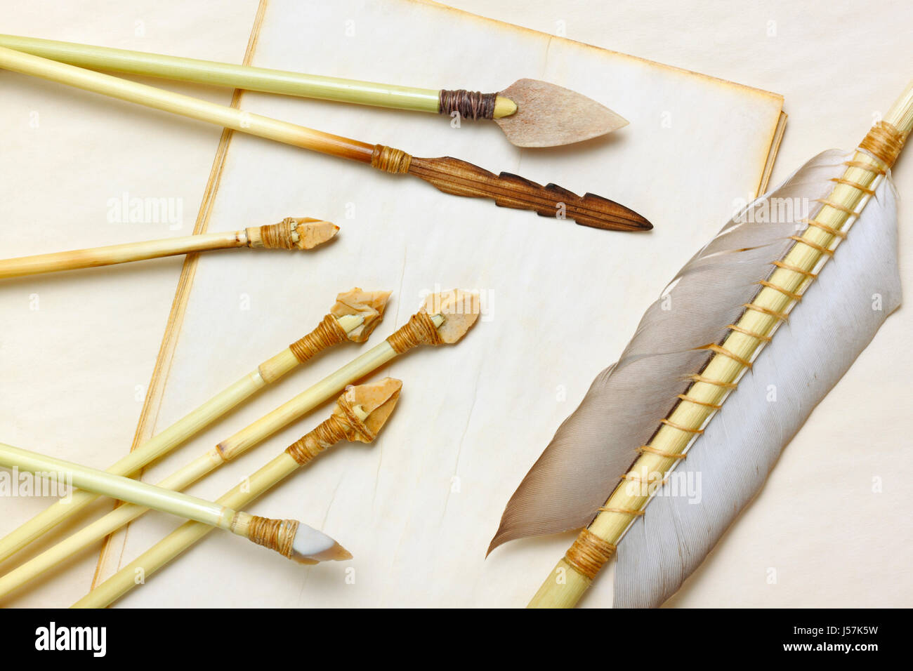 Primitivo della caccia e della pesca frecce con pietra focaia, legno e osso frecce su di età compresa tra i fogli di carta Foto Stock