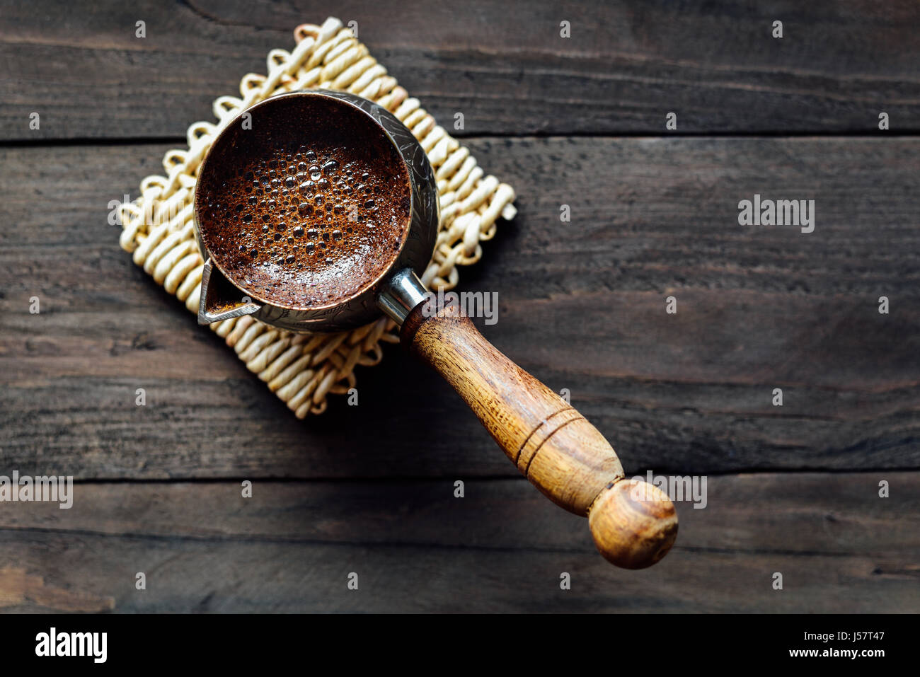 Caffe' macinato di fresco in turco cezve con schiuma su sfondo di legno Foto Stock