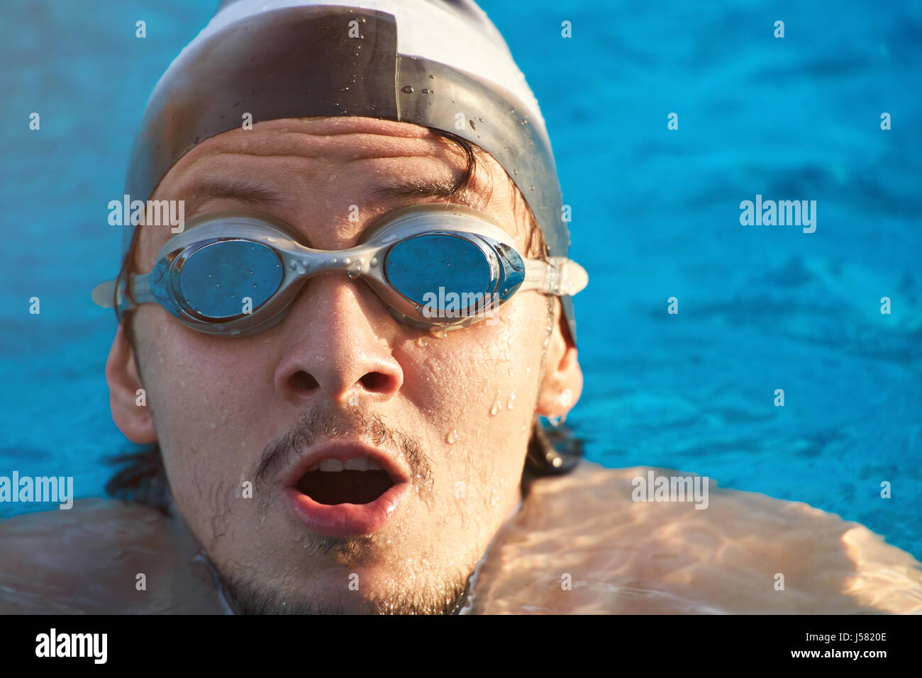 Nuotatore faccia su acqua blu sullo sfondo della piscina. Giovane uomo testa in acqua di piscina Foto Stock