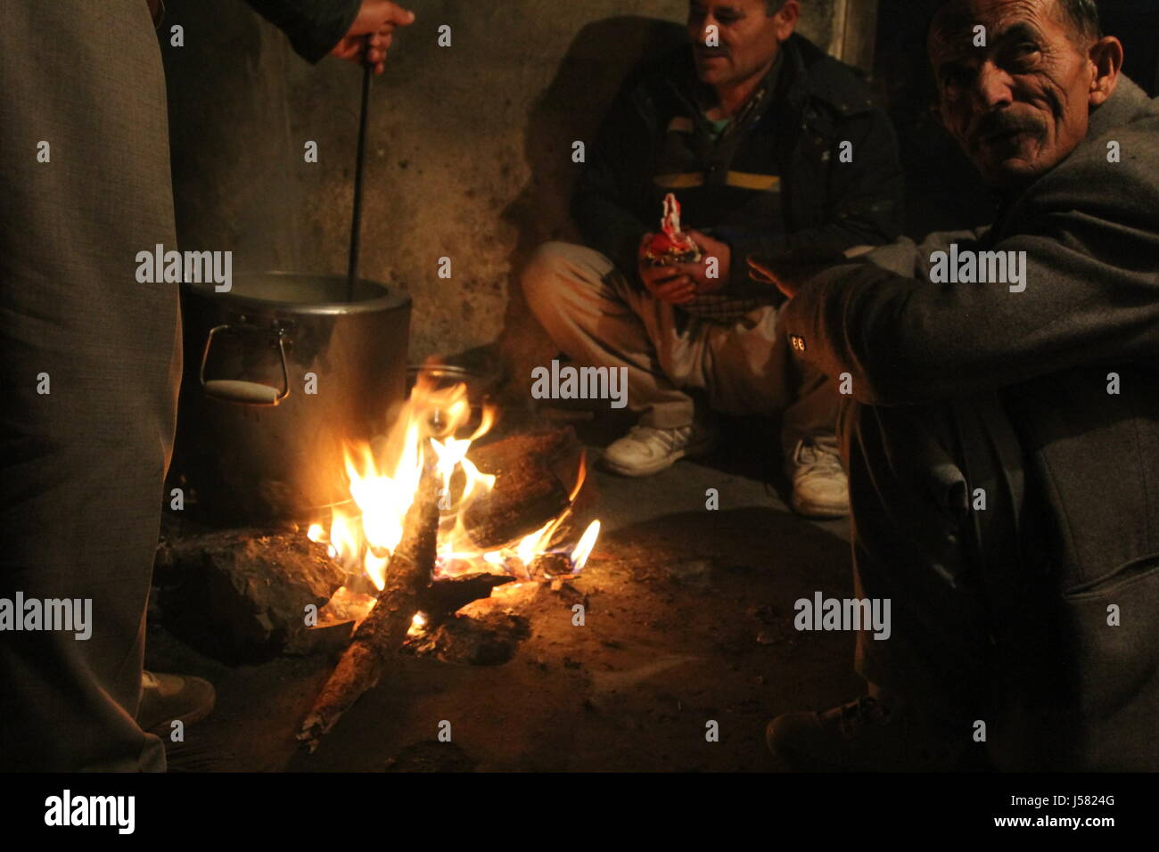 Gli uomini locali per la cottura su un fuoco di legno in una baita di montagna in India Foto Stock