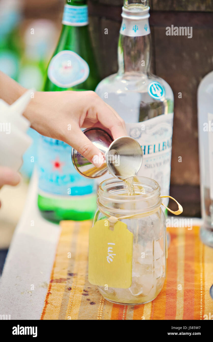Parte bevande miscelate, versando con jigger in mason jar. Foto Stock