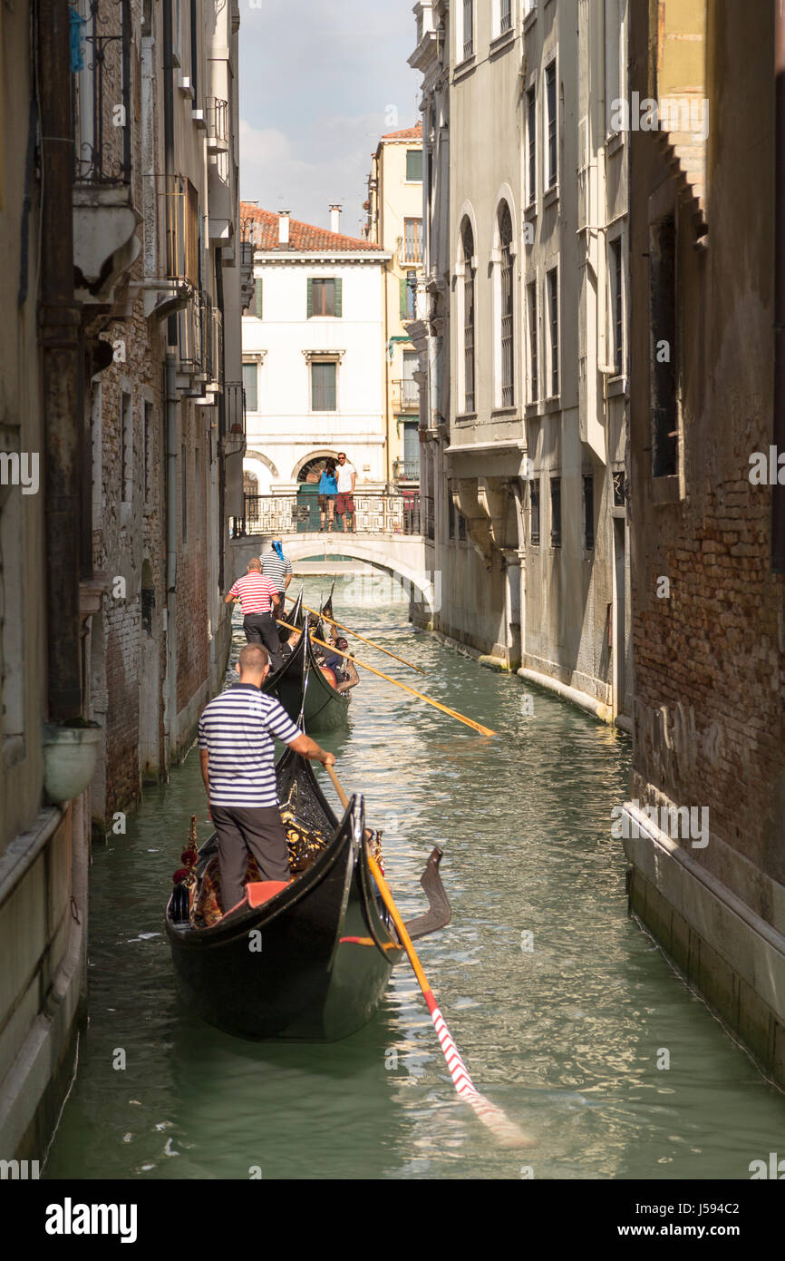 L'Italia, Venezia, una fila di gondole che stava trasportando i turisti intorno al lato canali di Venezia. Foto Stock