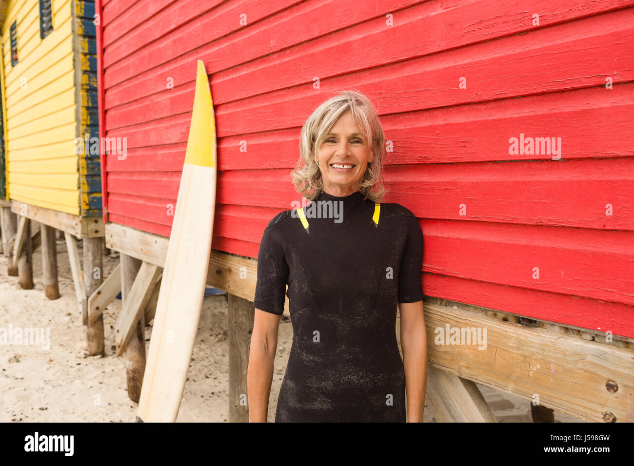 Ritratto di sorridere senior donna in piedi dalla capanna di rosso Foto Stock
