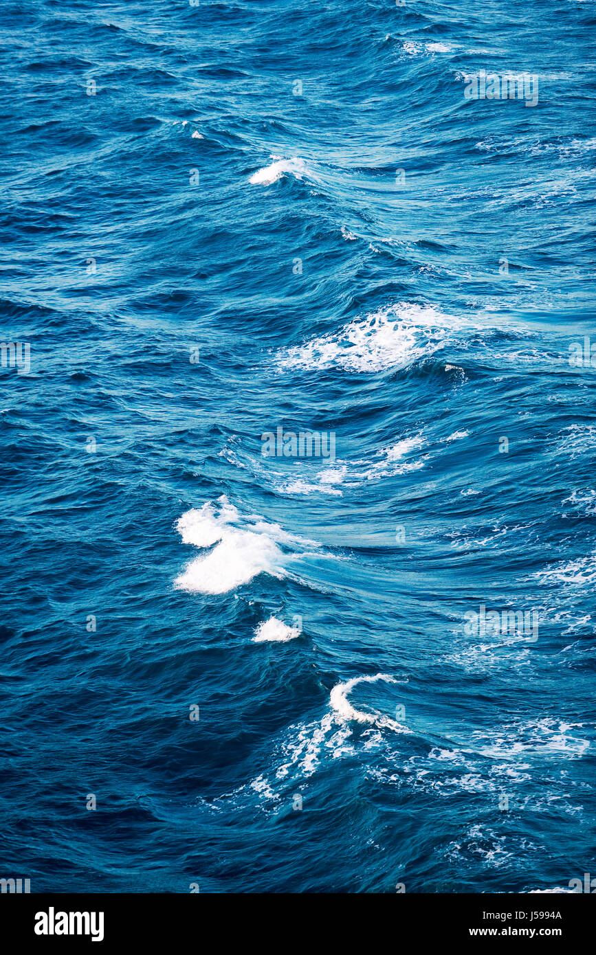 Le onde del mare con piccoli cappucci bianchi sullo sfondo Foto Stock