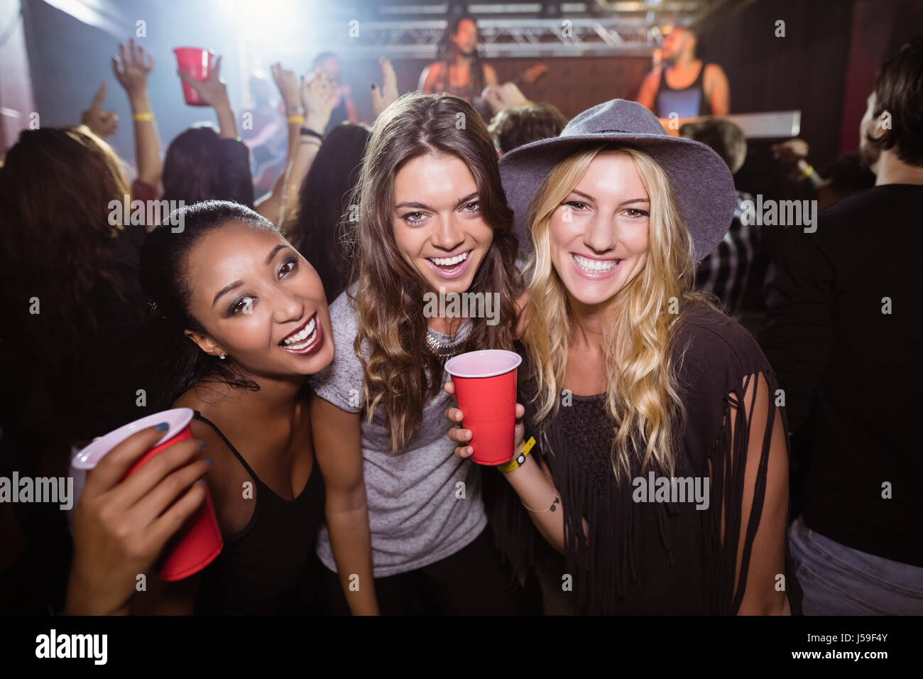 Ritratto di amici di sesso femminile con tazze monouso godendo la musica in discoteca Foto Stock