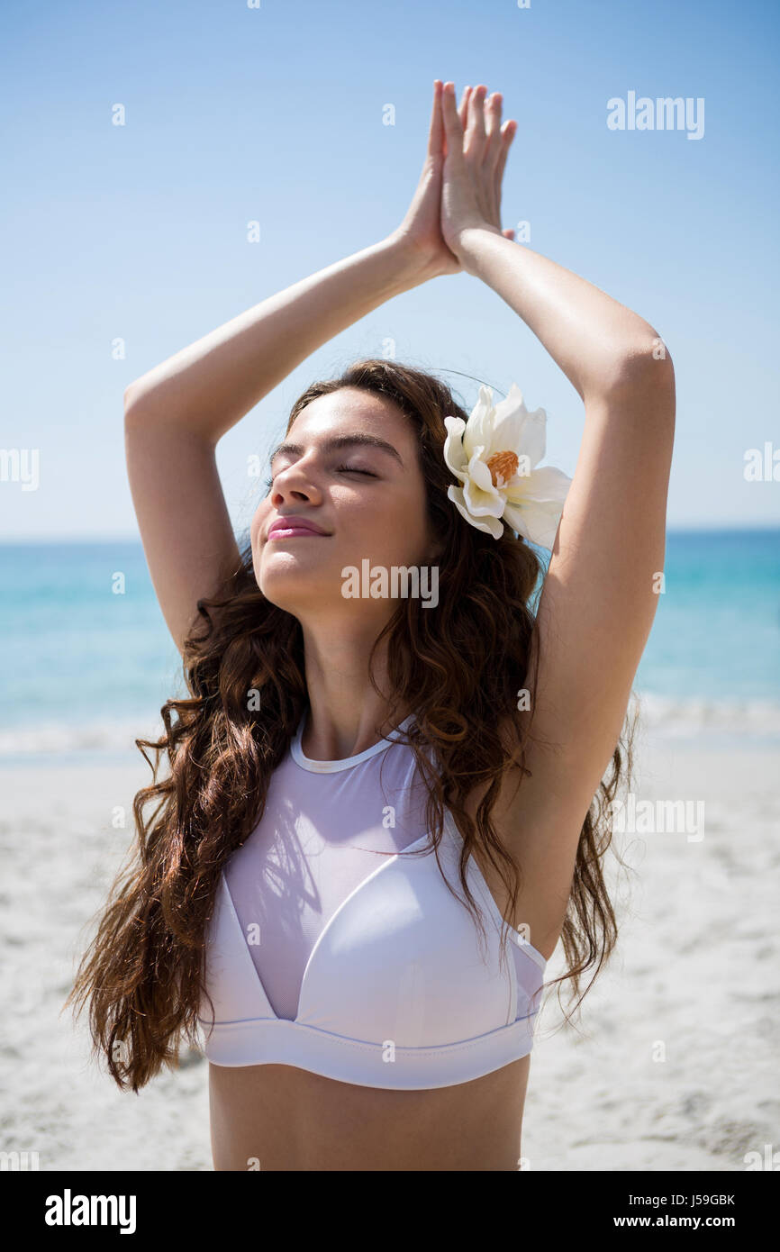 Close up di donna con gli occhi chiusi gli esercizi in spiaggia sulla giornata di sole Foto Stock